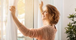 woman opening curtains